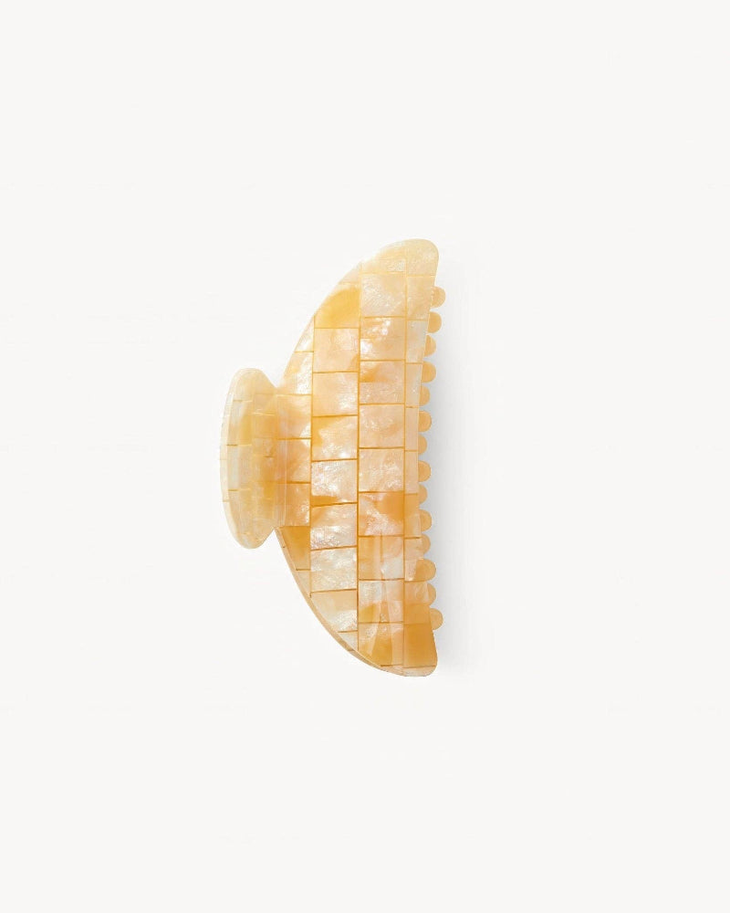 Decorative hair claw with a milky apricot color in a checkered pattern on a white background