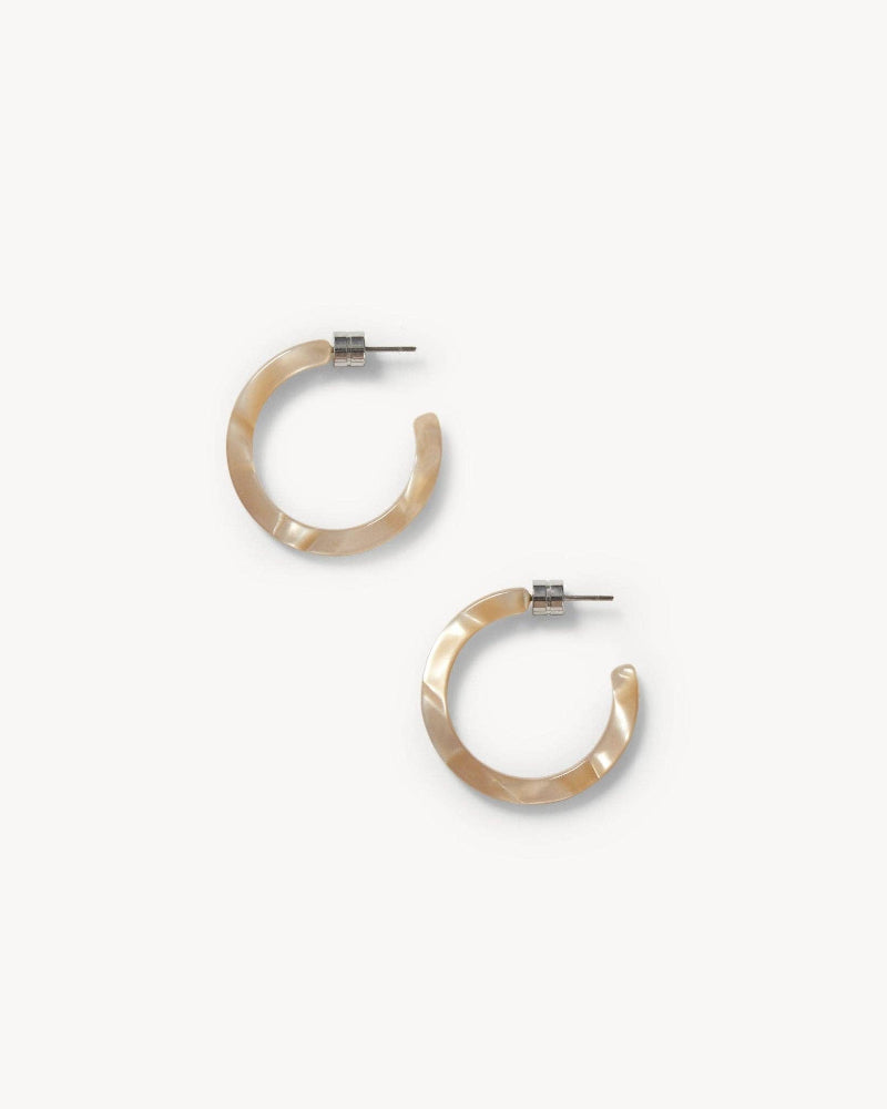A pair of round hoop earrings made of acetate in a sand shell color, displayed against a white background.