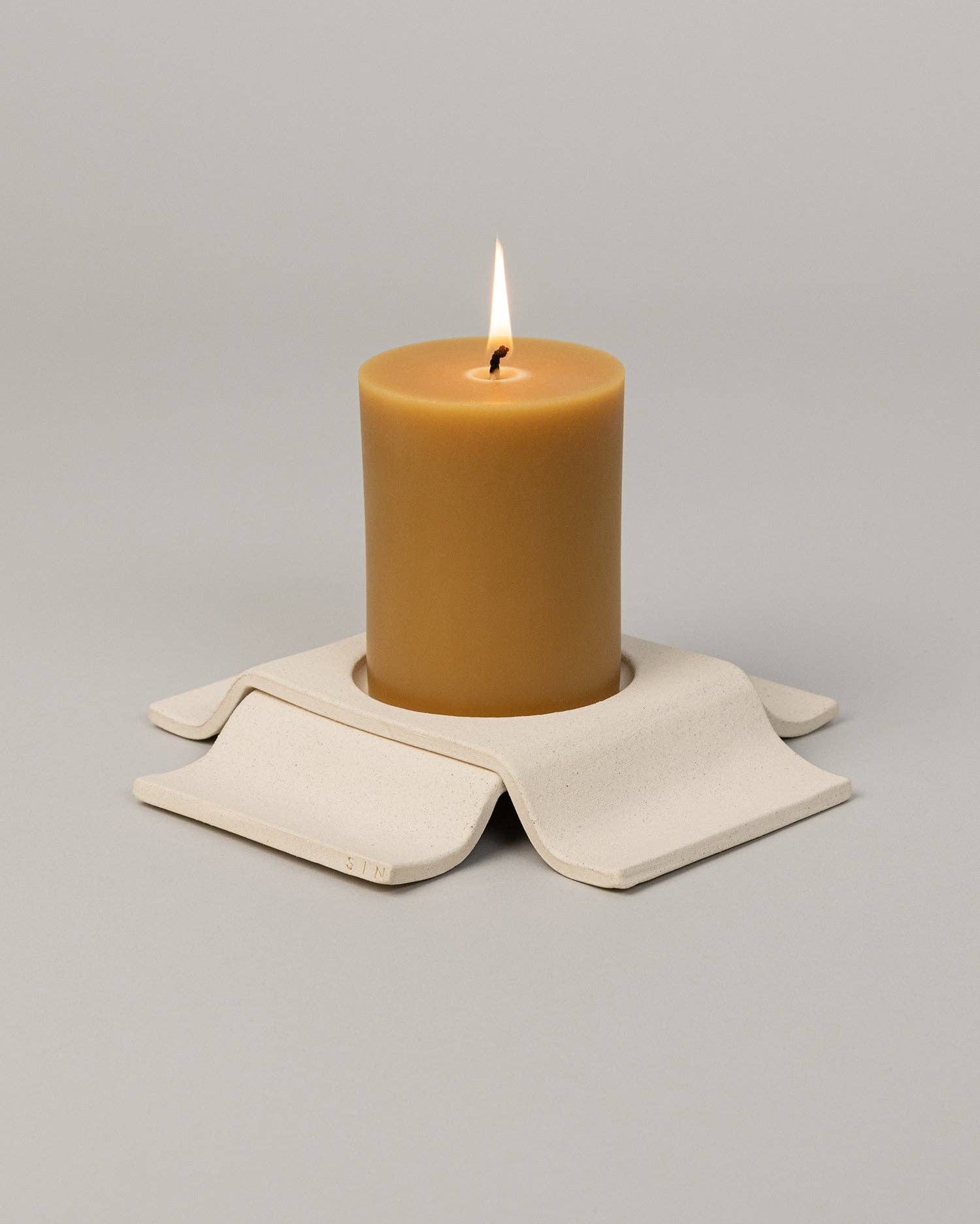 Brown candle on a beige coaster with a gray background