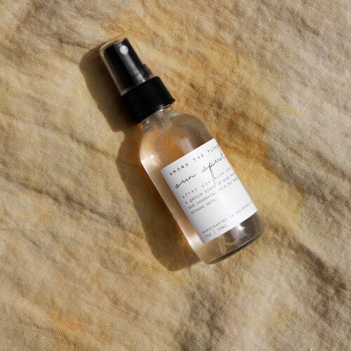 Small clear bottle with black spray top on a textured beige surface