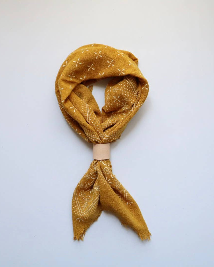 Mustard yellow patterned scarf on a light blue background