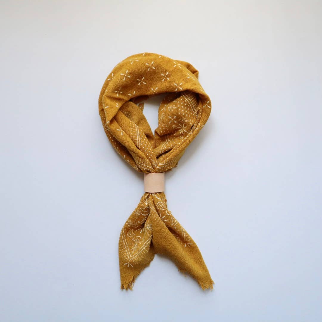 Mustard yellow patterned scarf on a light blue background