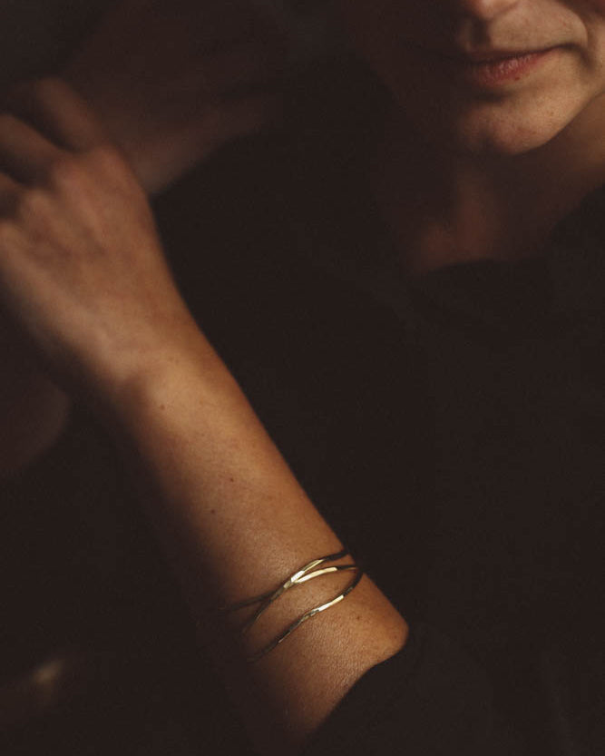 Women wearing two organic shaped gold bracelets