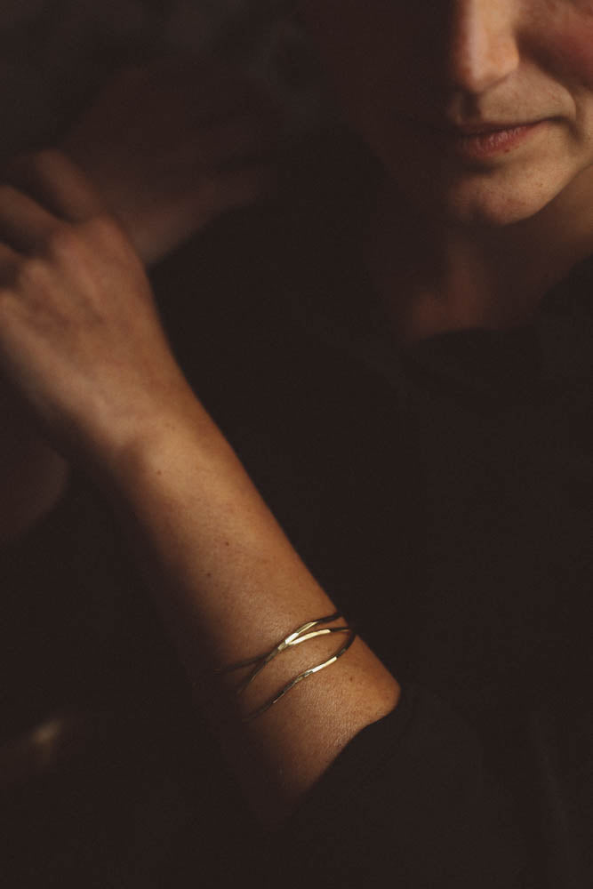 Women wearing two organic shaped gold bracelets