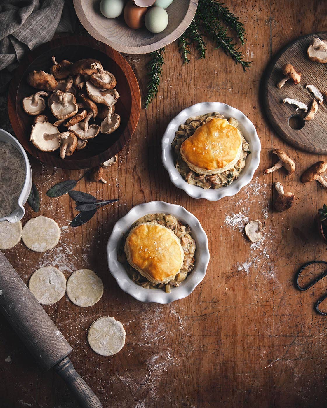 Wooden table with pies, mushrooms, and kitchen utensils