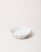 White ceramic dish with scalloped edge on a beige background