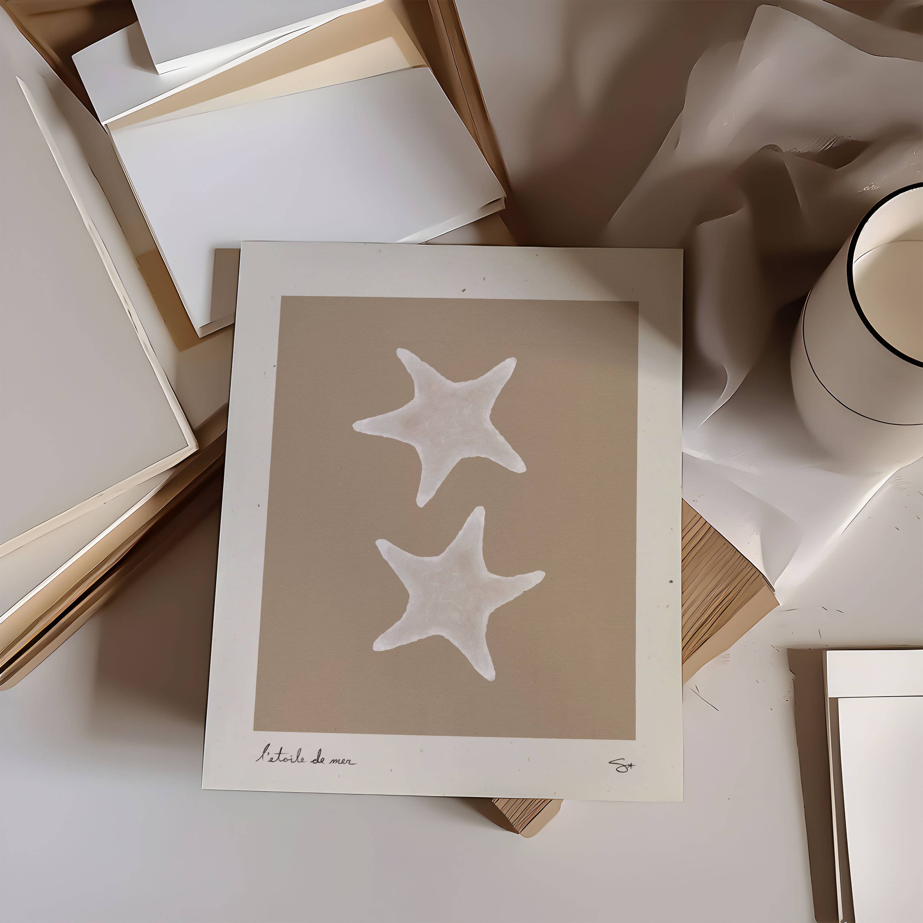 artwork with starfish design on a surface with books and a mug.
