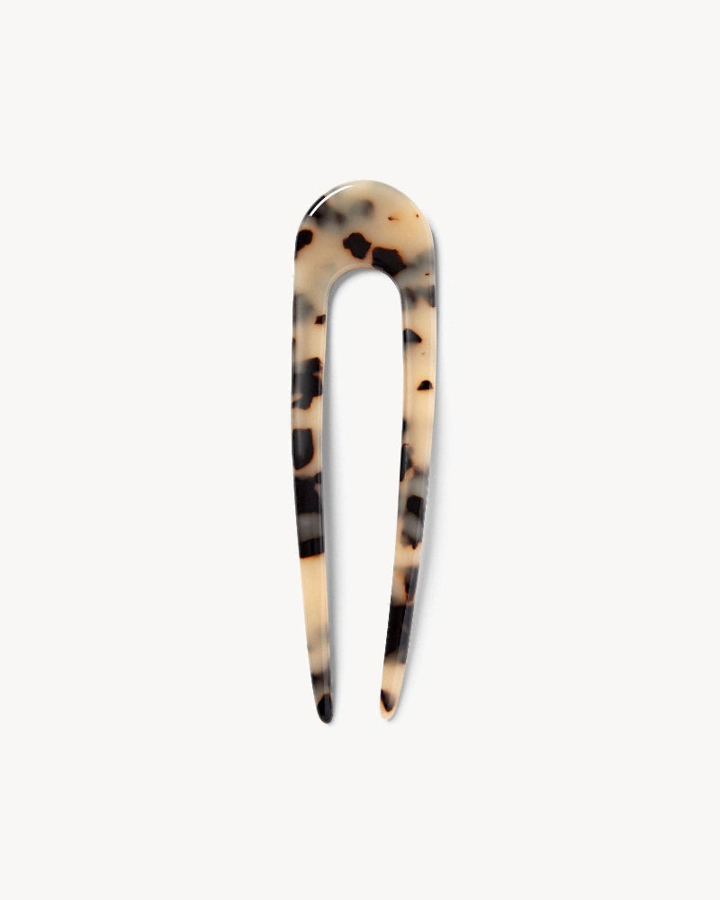 A blonde tortoise patterned French hair pin on a white background