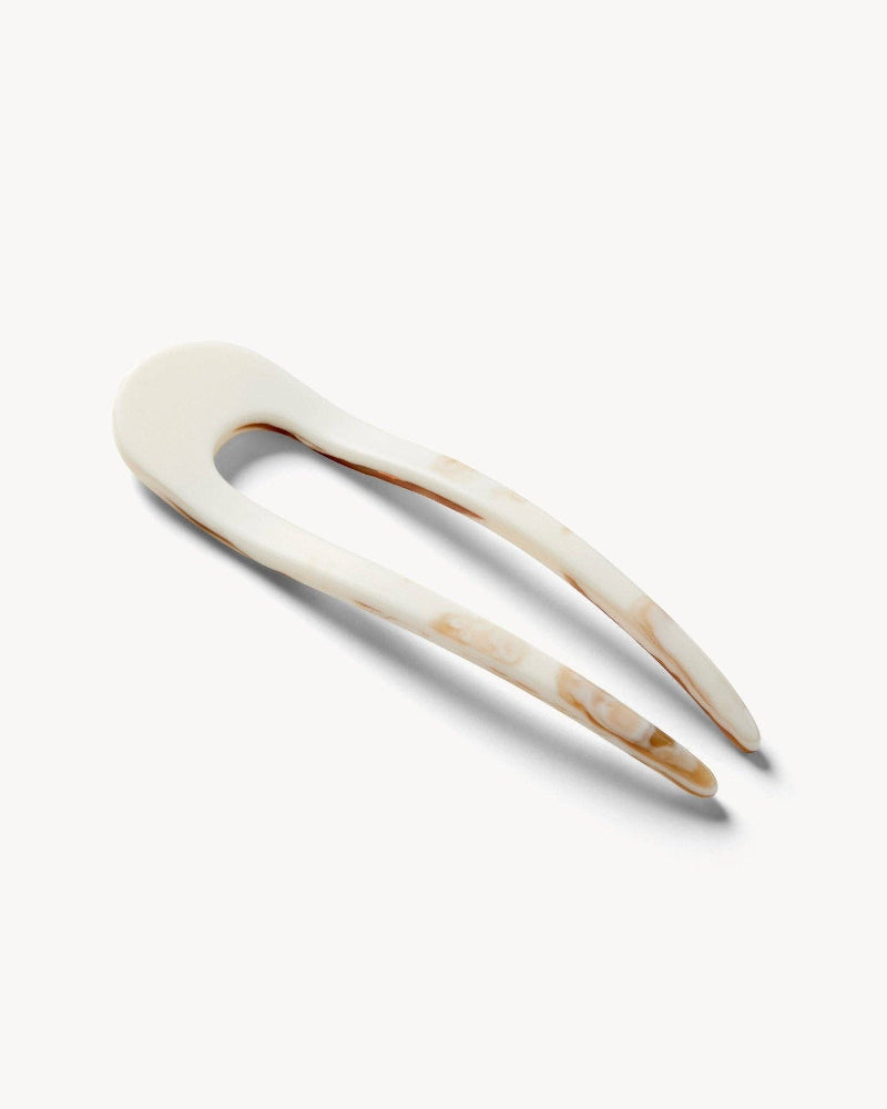 White marbled hair pin with brown accents on a white background