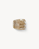 A beige mini claw clip made from bio-acetate, designed for holding hair.