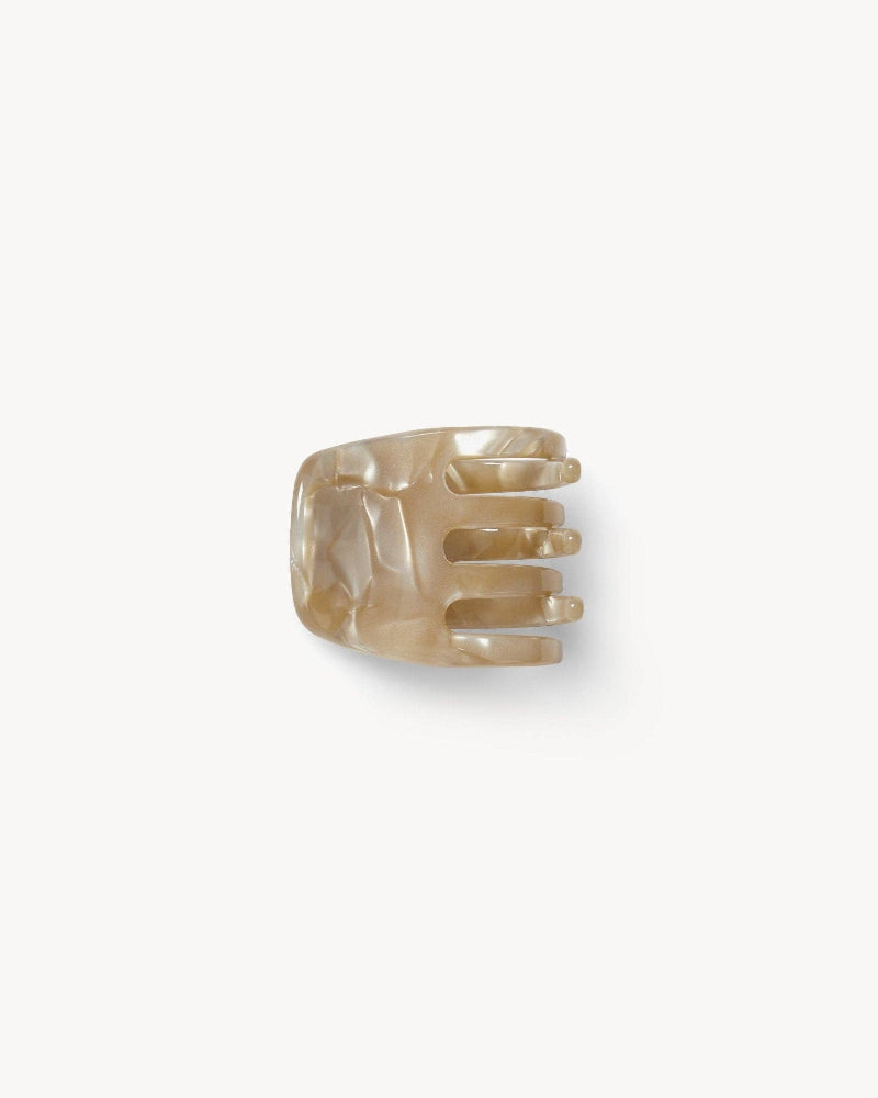 A beige mini claw clip made from bio-acetate, designed for holding hair.