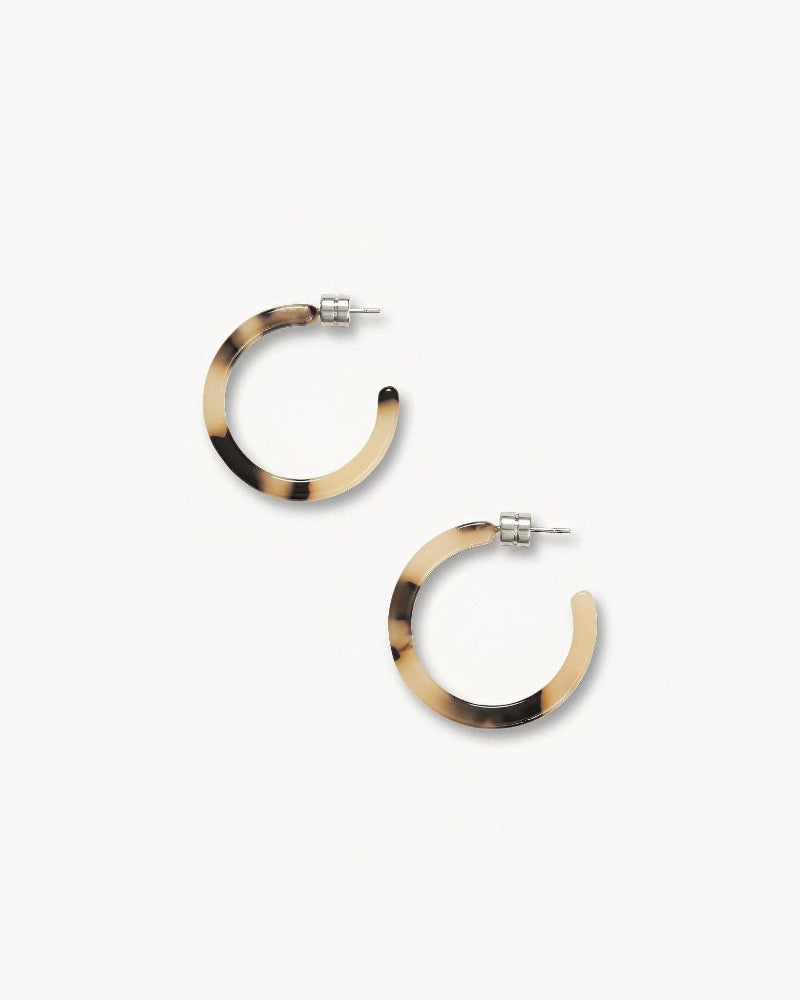 A pair of blonde tortoise pattern hoop earrings on a white background.