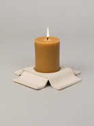 Brown candle on a beige coaster with a gray background