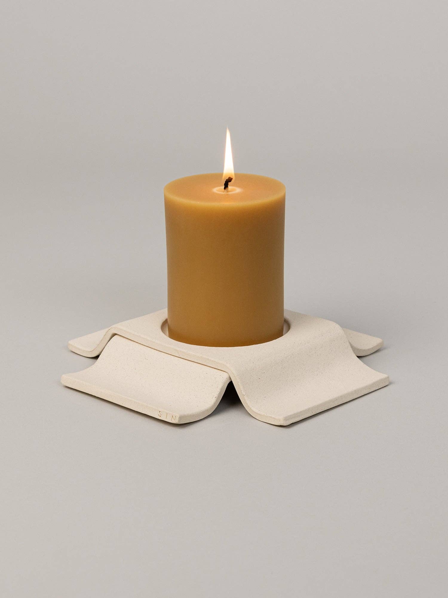 Brown candle on a beige coaster with a gray background