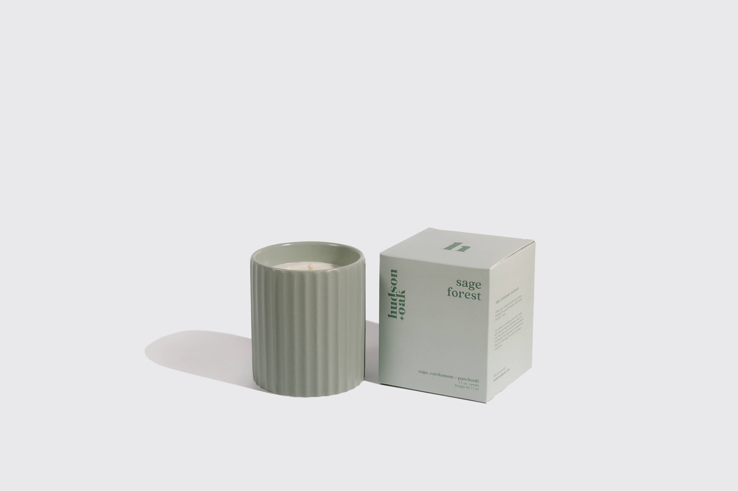 Scented candle with striped design and packaging labeled 'sage forest' on a light gray background