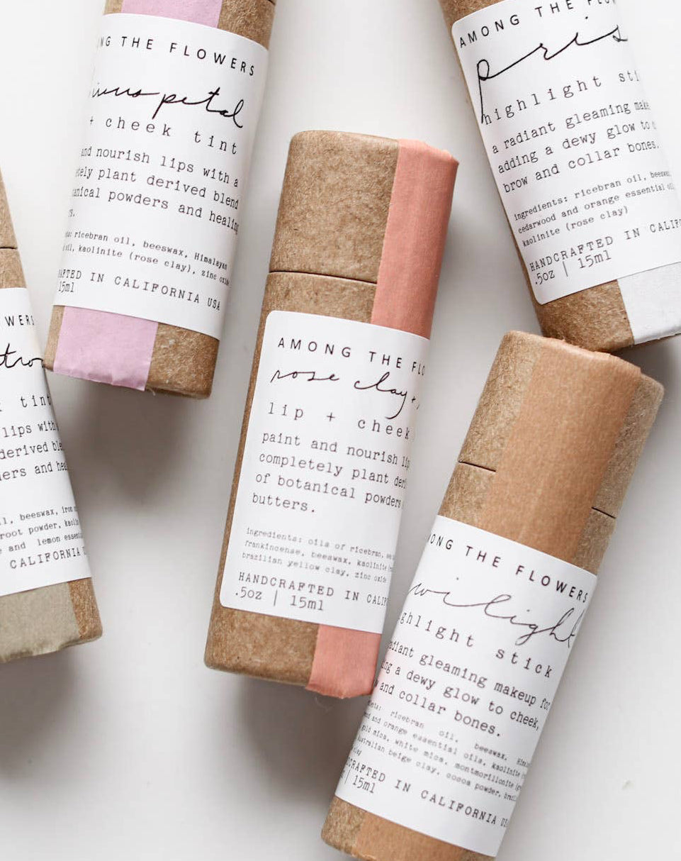 Five small cylindrical products with paper wrappings on a white background