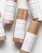 Five small cylindrical products with paper wrappings on a white background