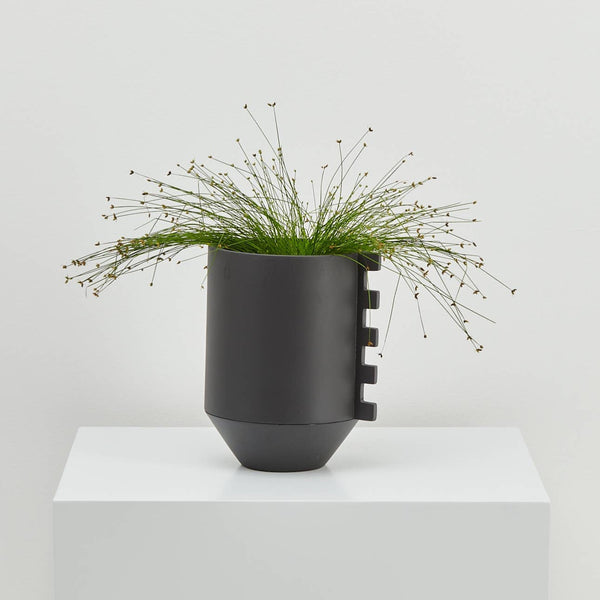 Modern black planter with shape accent and drainage tray.