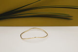 wavy hand forged brass bracelet styled with gold background and grass
